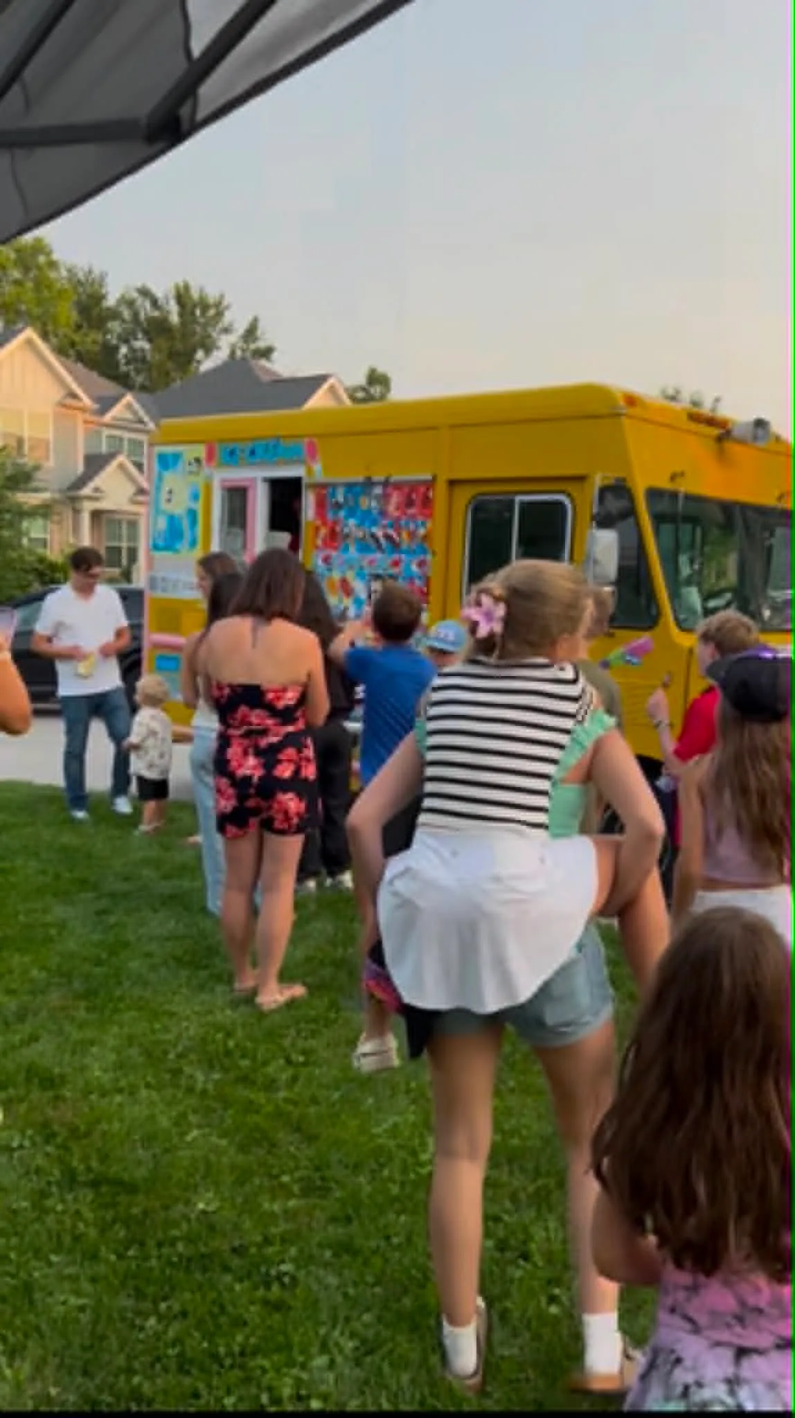 Guests lining up at the Tasty ice cream truck during a backyard party