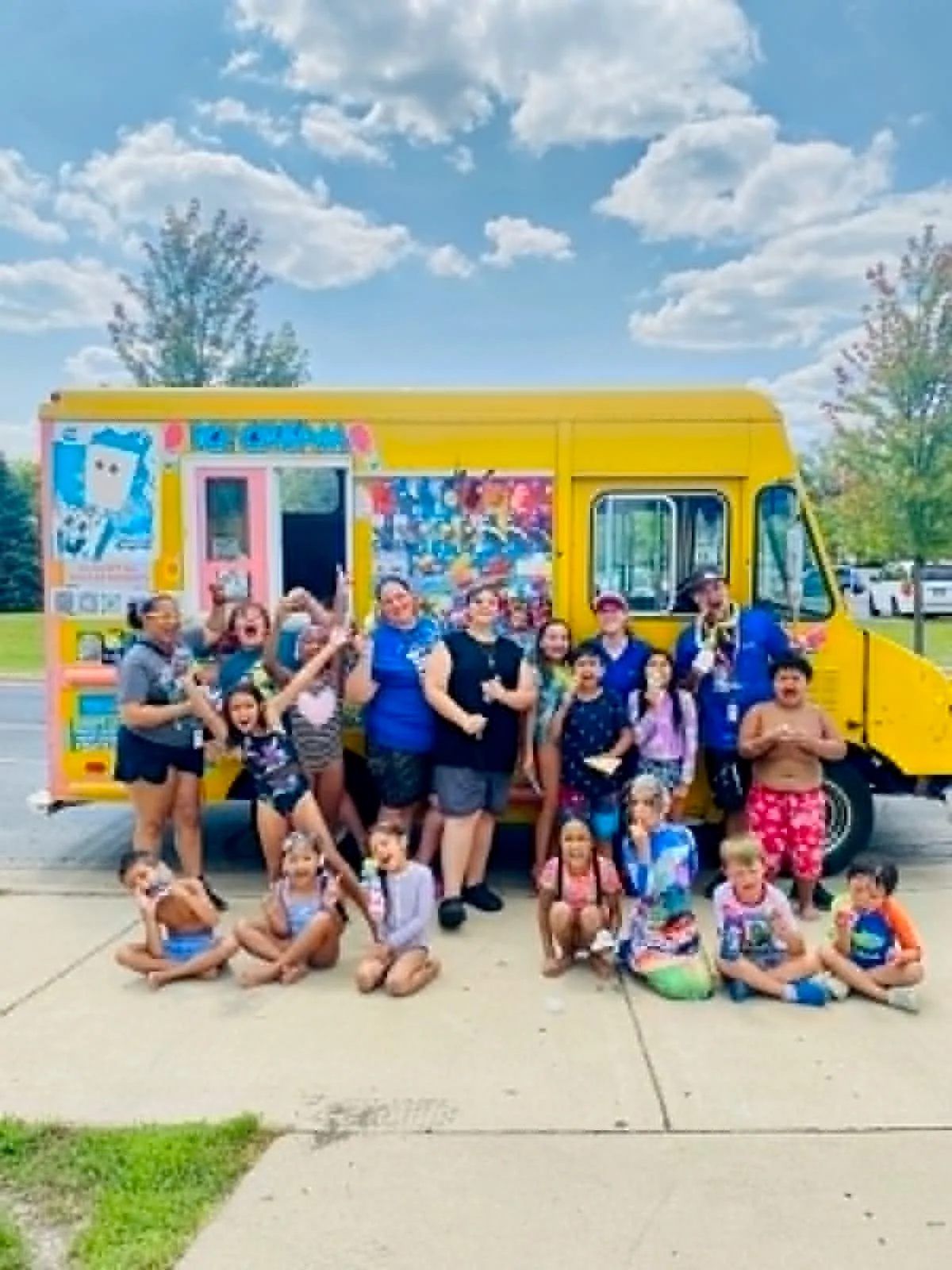 Kids and staff posing in front of the ice cream truck at a summer camp